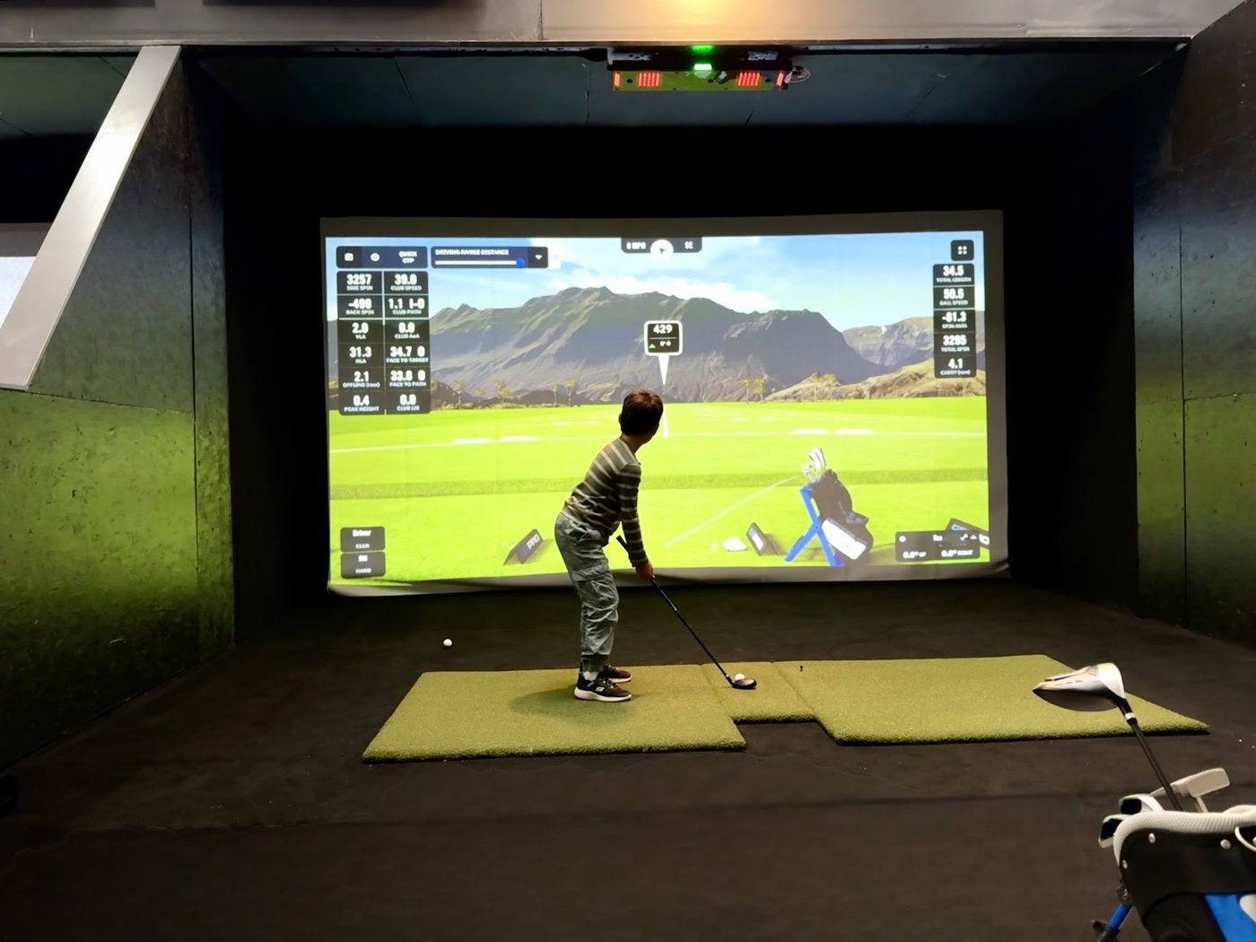 Junior golfer hitting on a simulator bay at COR Golf